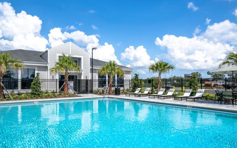 a swimming pool with palm trees and a building in the background